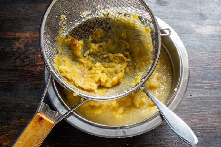 Making the apple purée Pressing soft apple mixture through a metal sieve with a spoon.