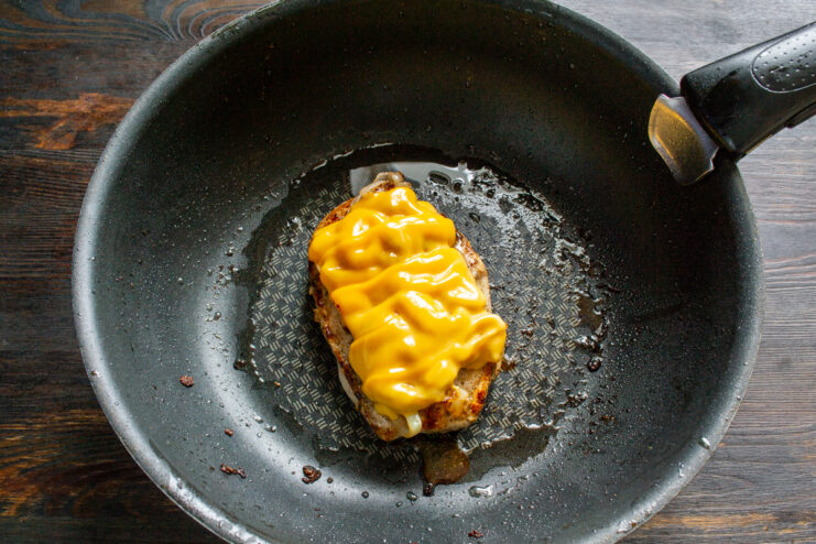 Melting cheese in the skillet Melted cheese over chicken cooking in a covered skillet
