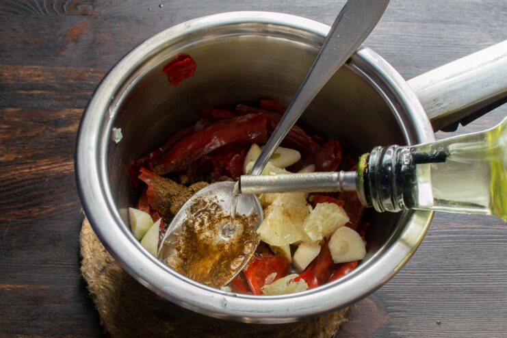 Adding oil to the sauce Pouring vegetable oil into a saucepan with Lazdjan sauce ingredients