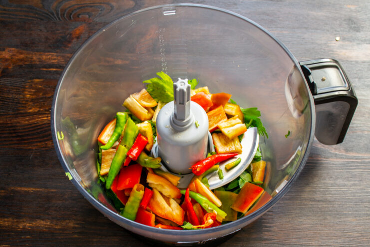 Adding finely chopped chili peppers for heat Bright chili peppers mixed with other chopped vegetables in the blender.