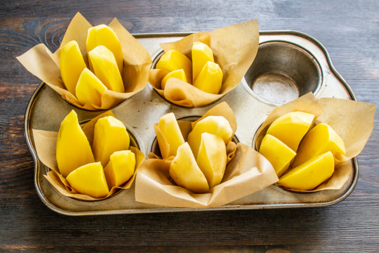 Quartered potatoes placed into parchment-lined cups