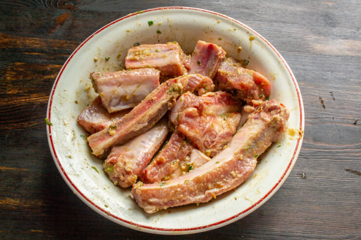 Marinating the Meat Raw pork ribs coated in oil and spice marinade in a bowl
