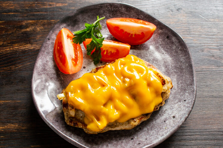 Serving the chicken breast Served chicken breast topped with melted cheese and fresh tomatoes