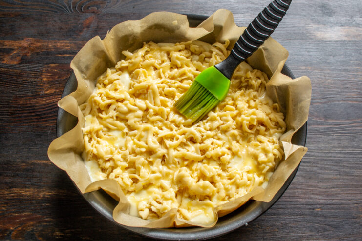 Brushing grated dough topping with egg wash using a pastry brush
