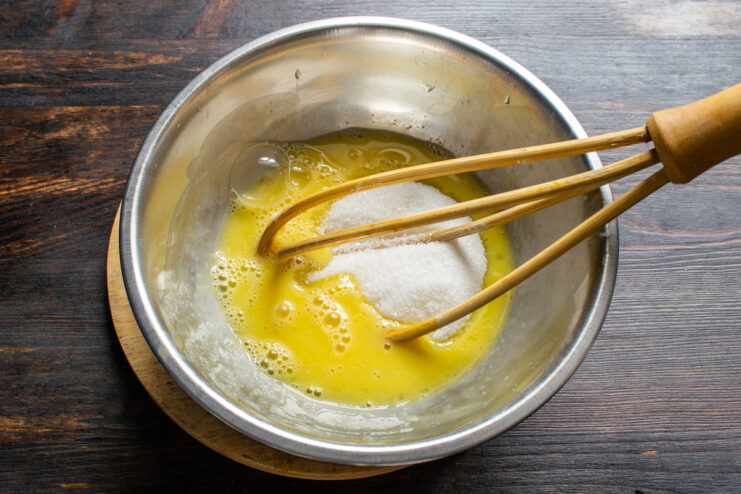 Whisking eggs with granulated sugar in a bowl until smooth