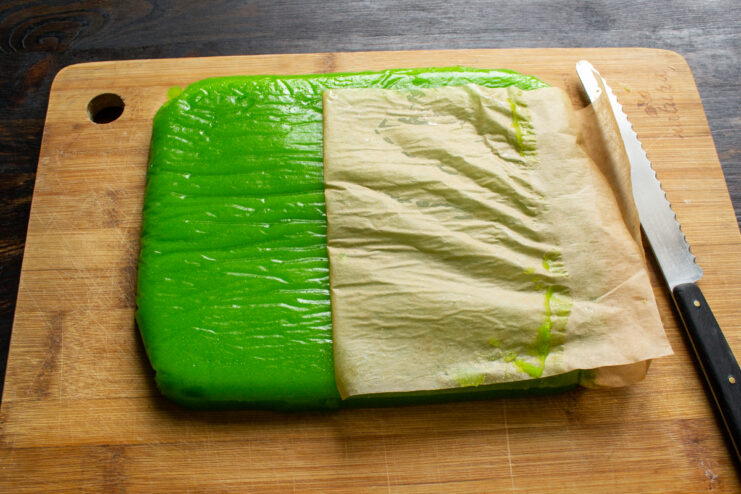 Removing from the dish Peeling parchment paper from a solid block of set green marmalade.