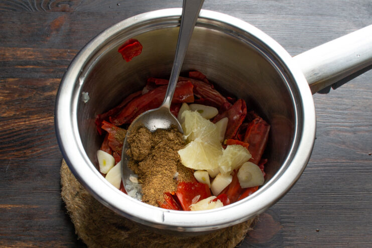 Adding dry spices Curry powder on a spoon being added to the saucepan with chili mixture