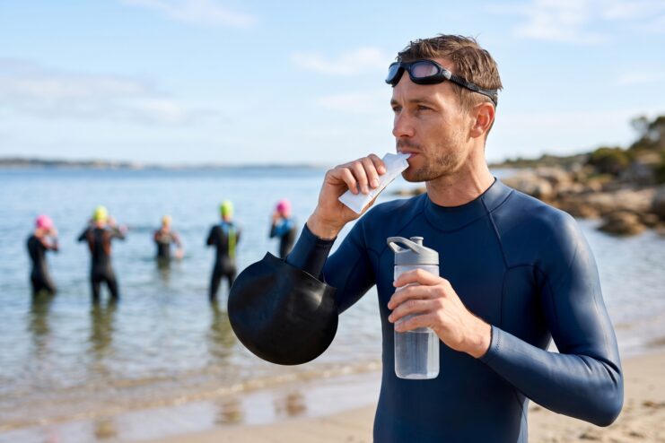 Athlete consuming energy gel A triathlete consumes an energy gel on the beach before a swim.