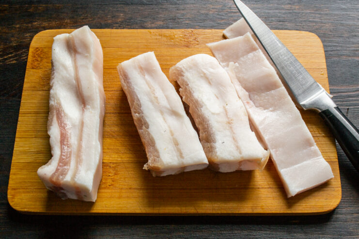 Slicing the skin off cured pork fat with a sharp kitchen knife