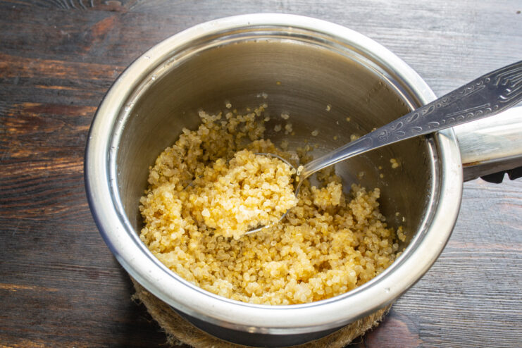 Cooked fluffy quinoa grains in a metal saucepan.
