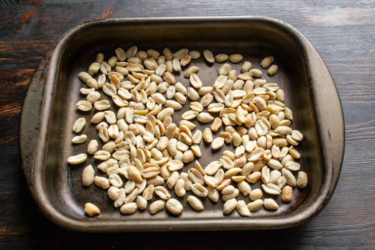 Preparing the peanuts Raw blanched peanuts spread evenly on a metal baking sheet
