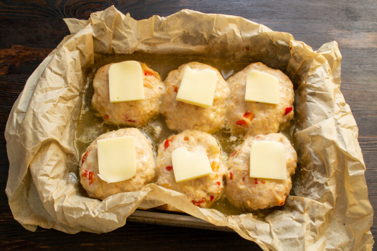 Adding the cheese topping Meatballs topped with cheese slices before the final baking
