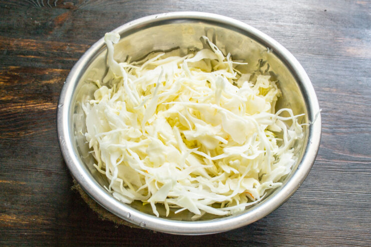 Thinly shredded fresh green cabbage in a deep bowl.