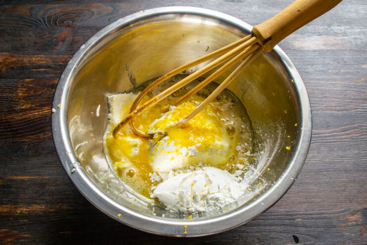 Combining cheese, lemon, eggs, and starch in a mixing bowl