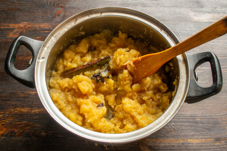 Simmering apples into a smooth puree Reduced apple puree simmering in a pot with spices and a wooden spatula.