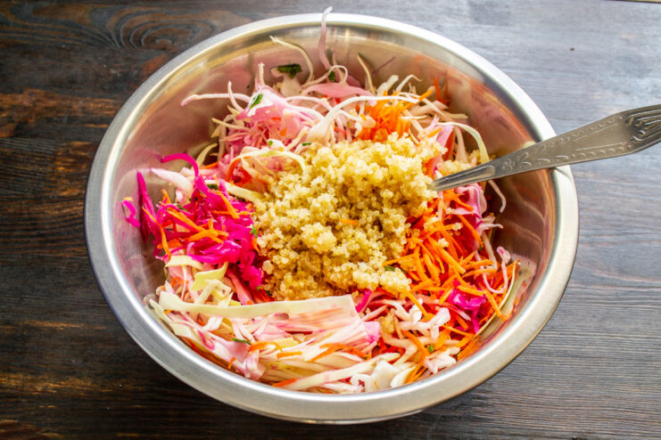 Cooked quinoa being folded into the colorful vegetable mix.