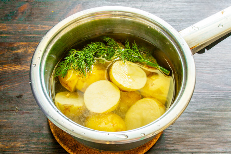 Boiling new potatoes in a pot with fresh dill