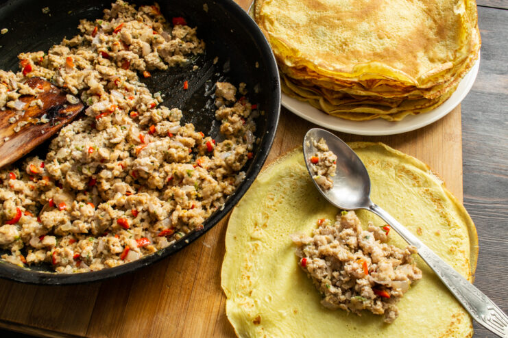 Stuffing The Crepes Adding a spoonful of meat filling to the center of a thin crepe
