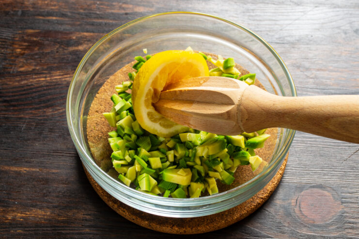 Adding Lemon Juice Squeezing fresh lemon juice over diced avocado