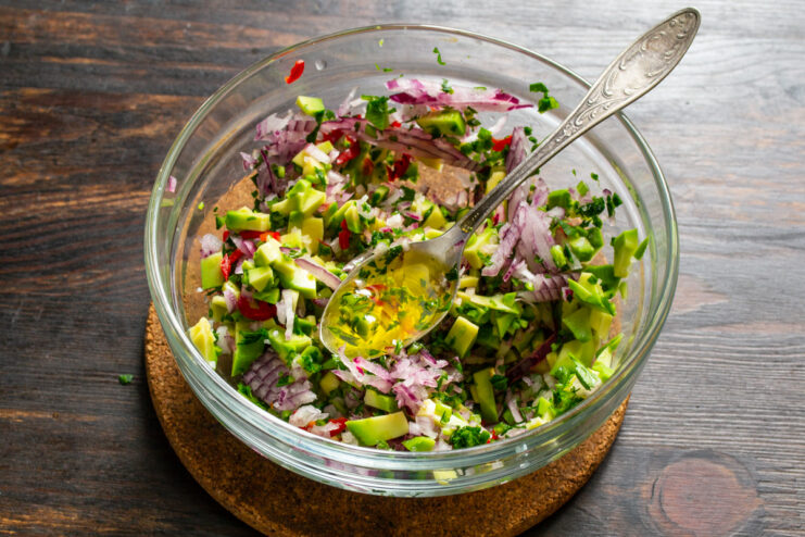 Dressing with Olive Oil Pouring olive oil into guacamole in a glass mixing bowl