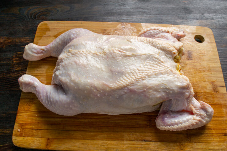 Folding the edges of the chicken skin around the layered crepe filling.