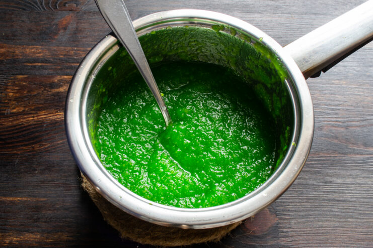 Heating the mixture Green apple purée simmering in a saucepan on the stove.
