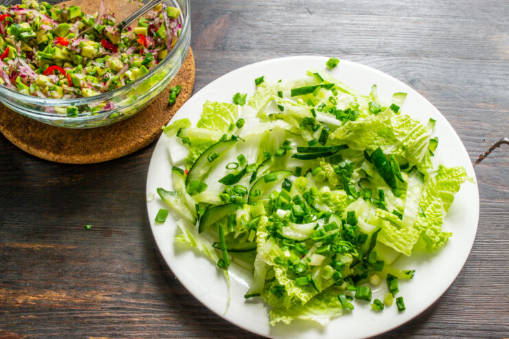 Sprinkling with Scallions Chopped scallions sprinkled over cabbage and cucumbers on a plate
