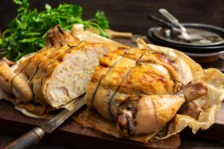 Sliced golden-brown crepe-stuffed chicken on a wooden cutting board.