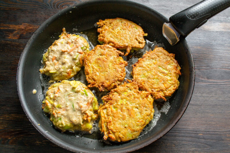 Golden fritters frying on one side in a pan